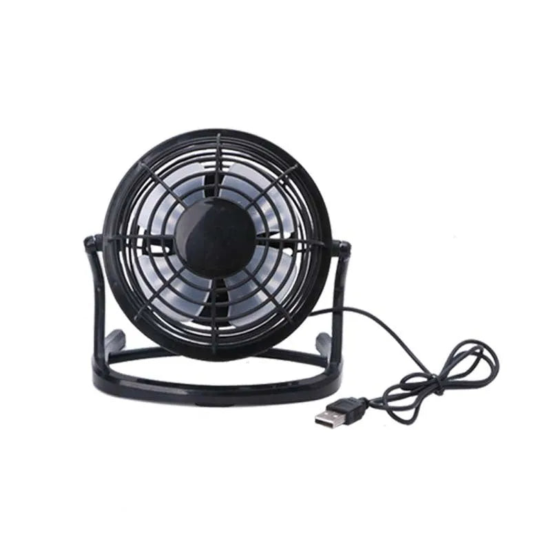 Small black USB desk fan with adjustable tilt on a wooden desk next to a laptop