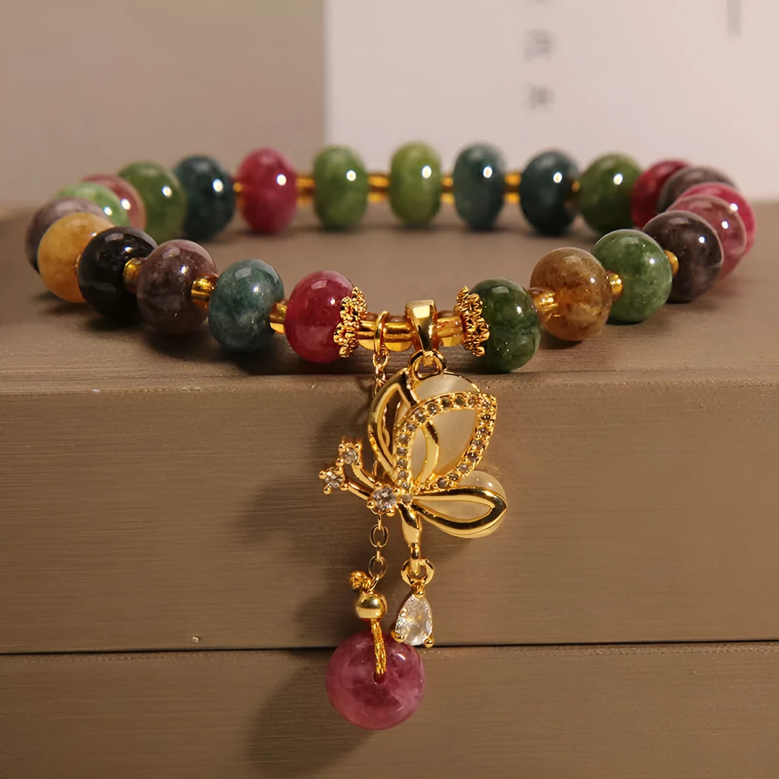 Colourful women's bracelet with a silver butterfly charm, colourful beads, and green tourmaline stones.