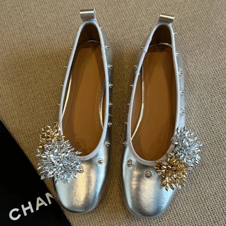 Women's silver Mary Jane flat shoes with flower rivets and a buckle strap on a sheepskin upper.