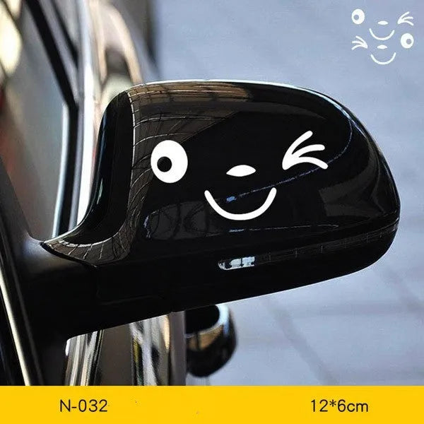 Pair of reflective cartoon eye car stickers on a vehicle rearview mirror.