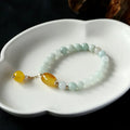 Women's ethnic style geometric bracelet with hanging agate tassel and 14K gilded details.