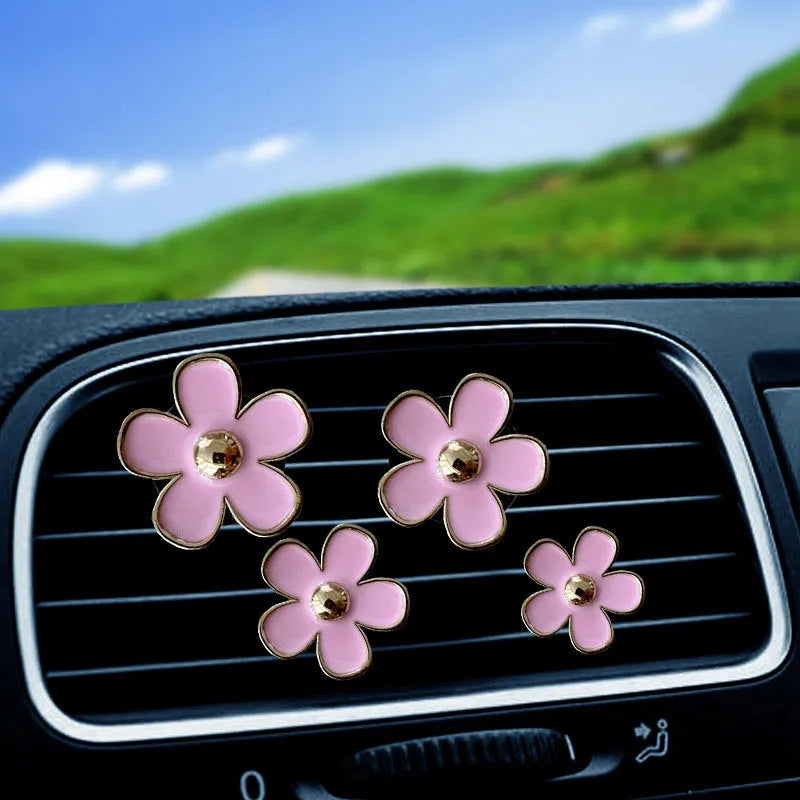 Set of four metal flower-shaped car vent aromatherapy clips in assorted colours