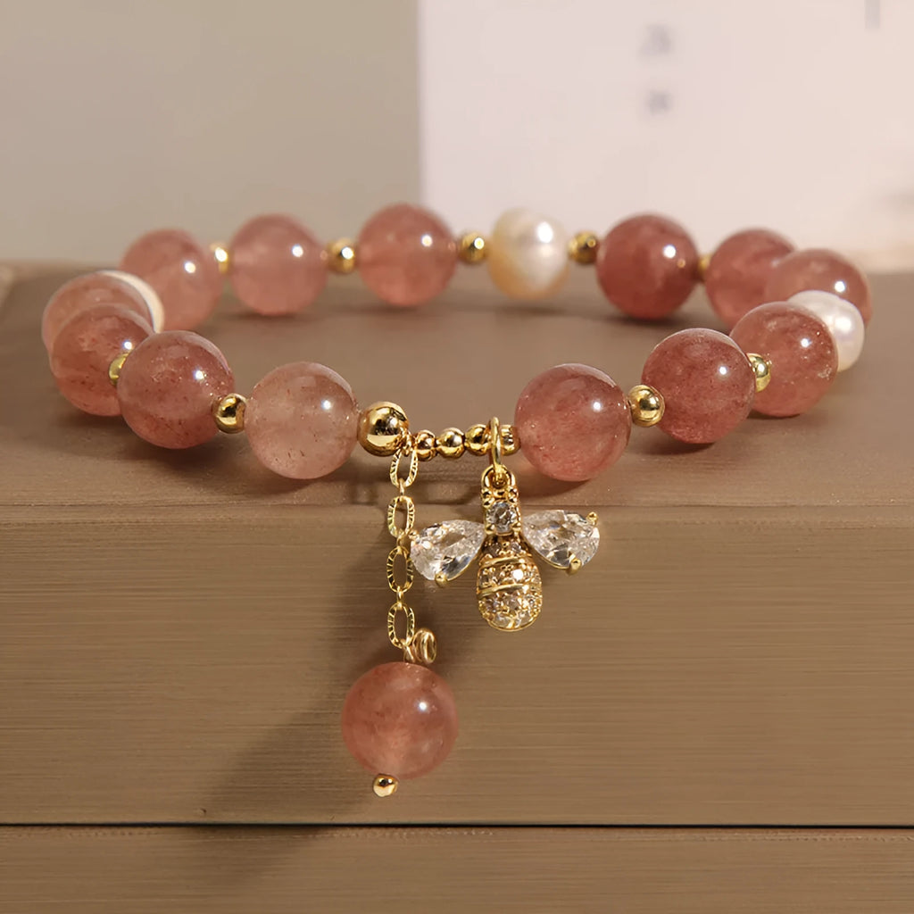 Adjustable pink strawberry quartz bracelet with three freshwater pearls and sparkling zircon charms on a wrist.