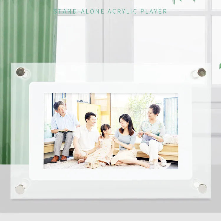 White vertical digital picture frame with acrylic casing on a table, showing a family photo on screen.