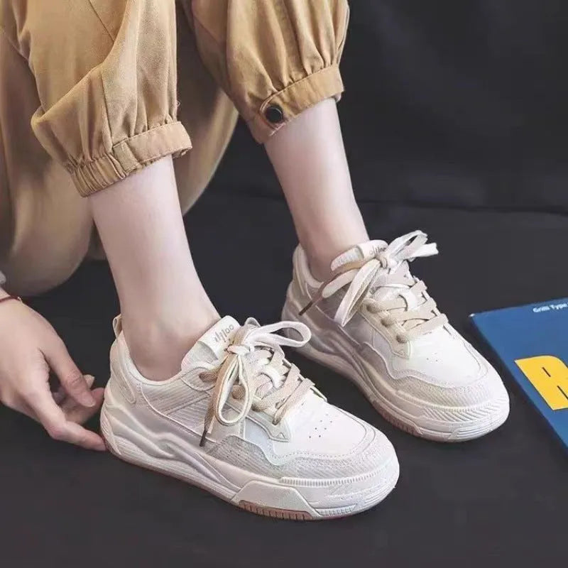 Women's pink and white low-top sneakers with a height-increasing rubber sole on a neutral background.