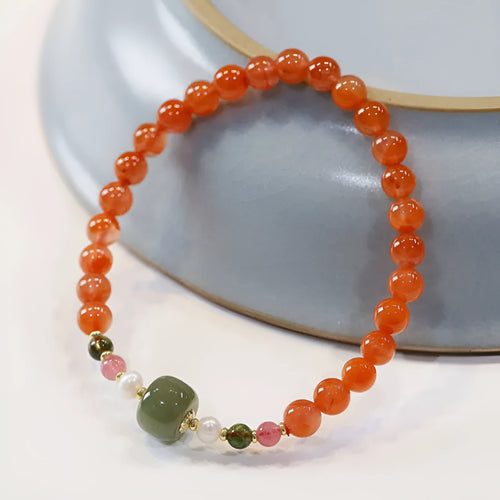 Women's bracelet made of round red South agate beads from Sichuan on a black elastic cord.