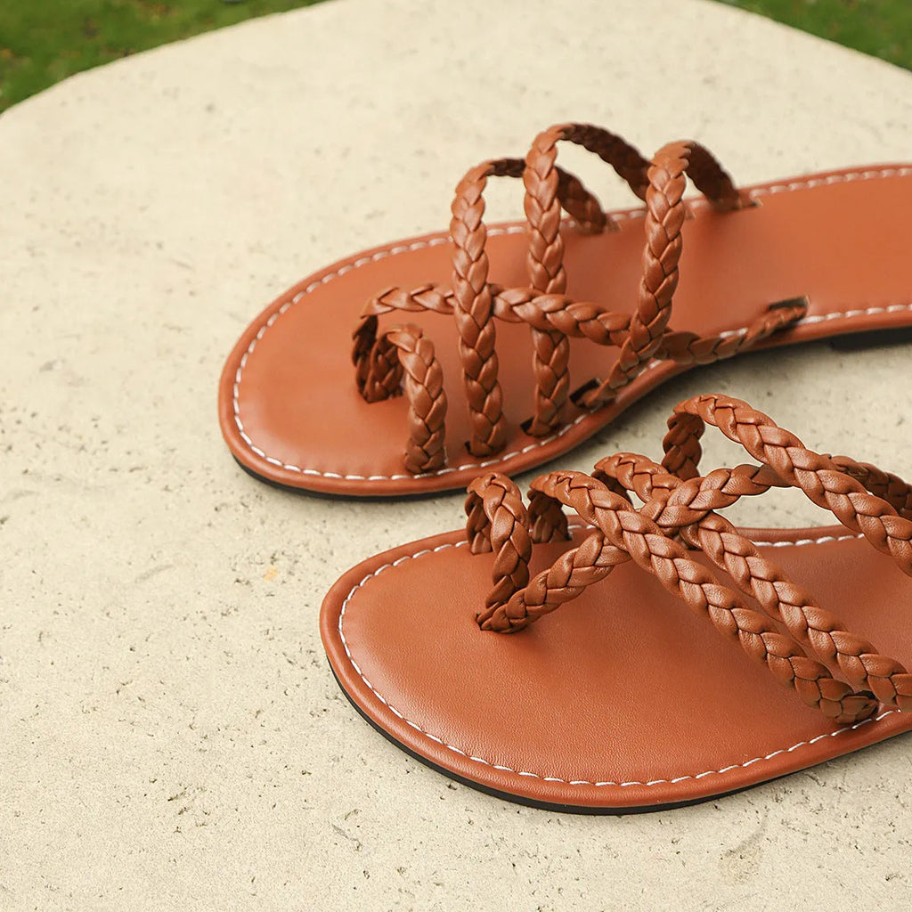 Women's woven clip-toe flat sandals in white, black, and brown on a summer background.
