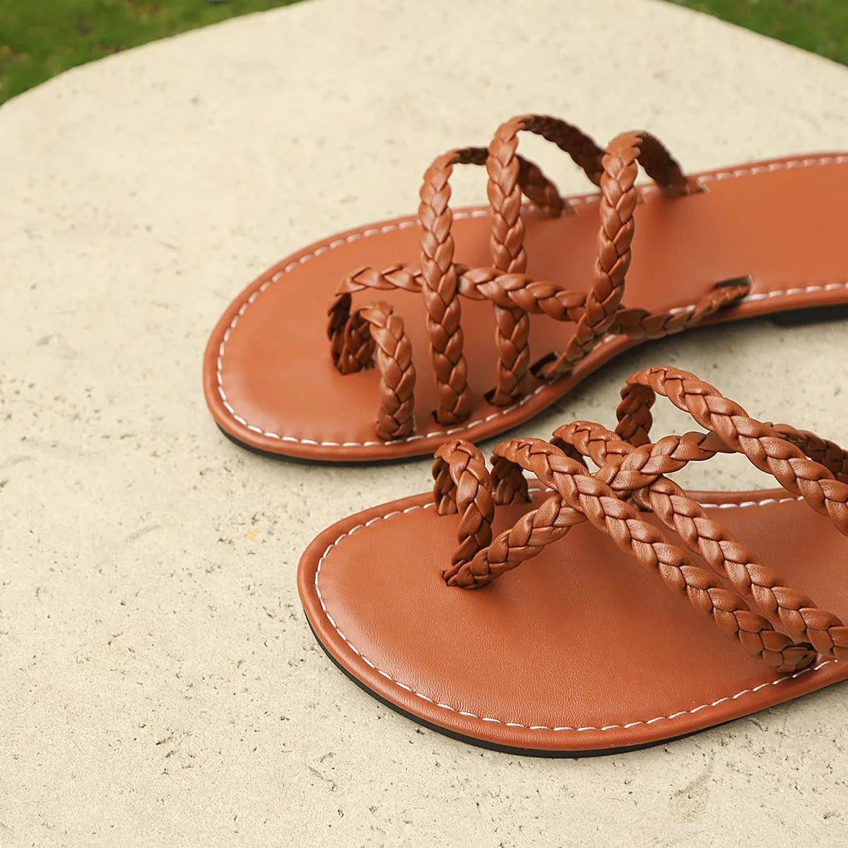 Women's woven clip-toe flat sandals in white, black, and brown on a summer background.