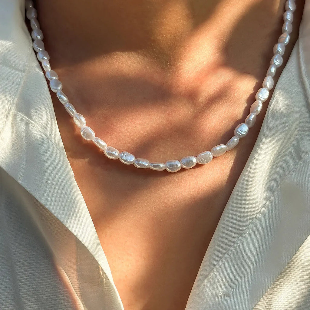 White U-shaped men's imitation pearl necklace with shellfish pendant on pearl chain.