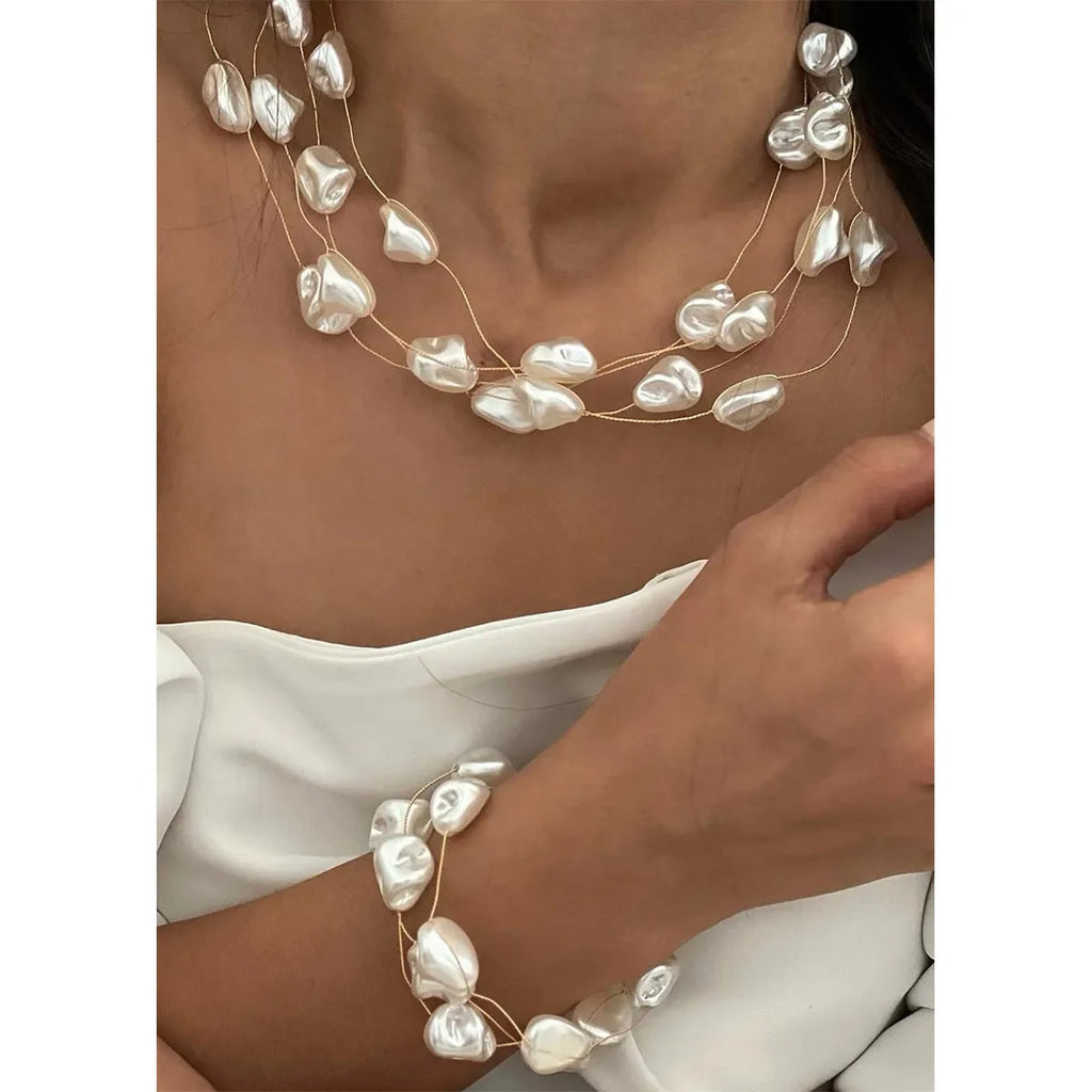Gold-tone baroque imitation pearl necklace and bracelet set with U-shaped pendant on woman