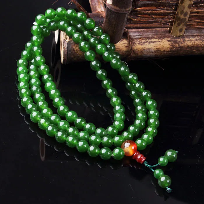 Jade green spinach green quartz rock rosary bracelet with 108 beads and a Buddha head on a wrist.