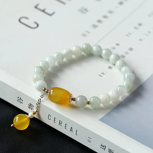 Women's ethnic style geometric bracelet with hanging agate tassel and 14K gilded details.