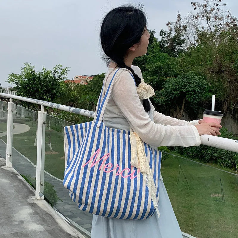 Blue, pink, and white striped canvas bag with printed letters on the front.