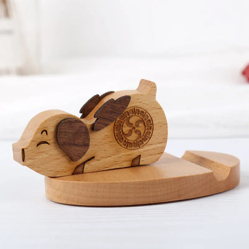 Beech wood and resin lazy bracket mobile phone holder in an animal design style on a desk.