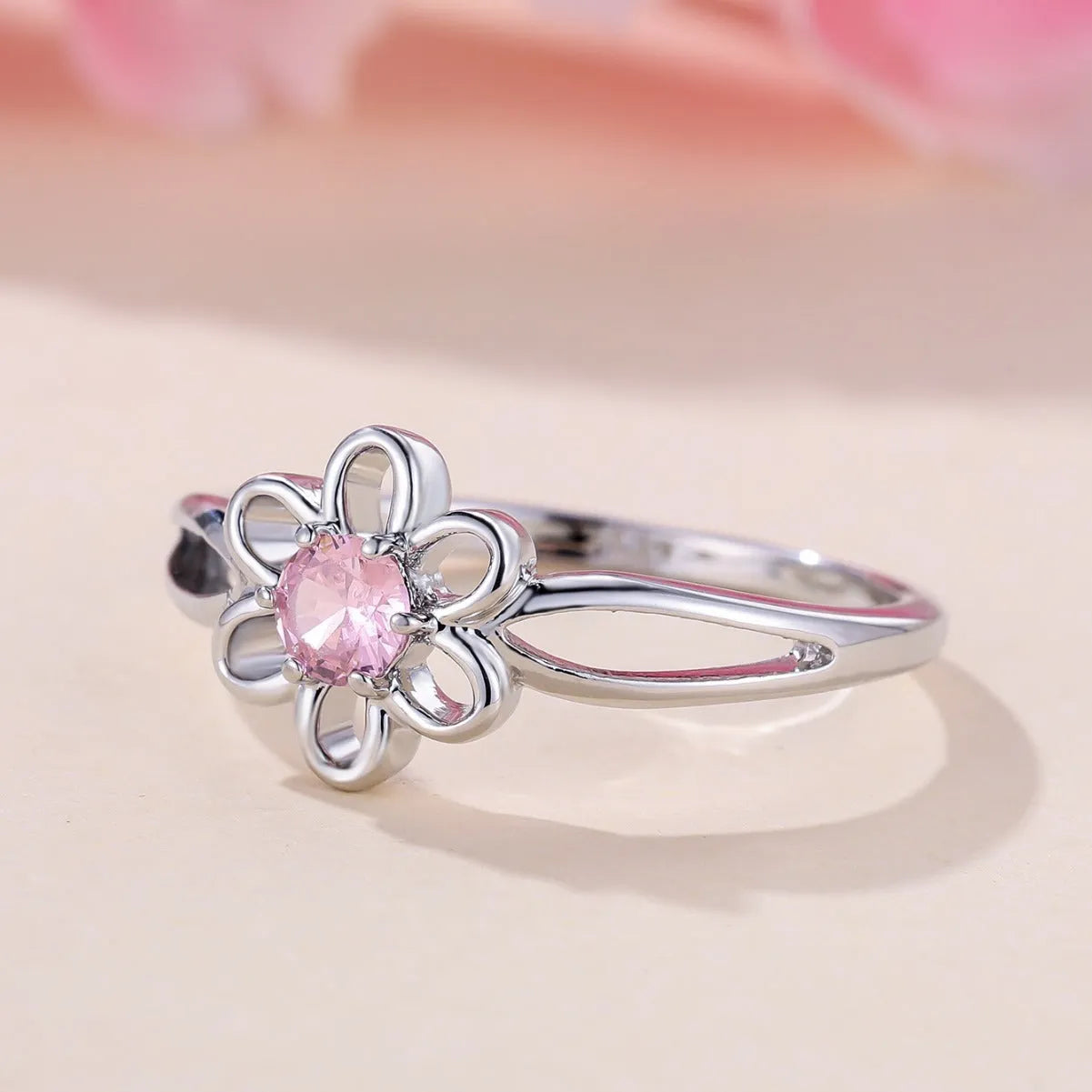 Women's hollowed flower fashion ring in electroplated platinum pink diamond colour on a white background.