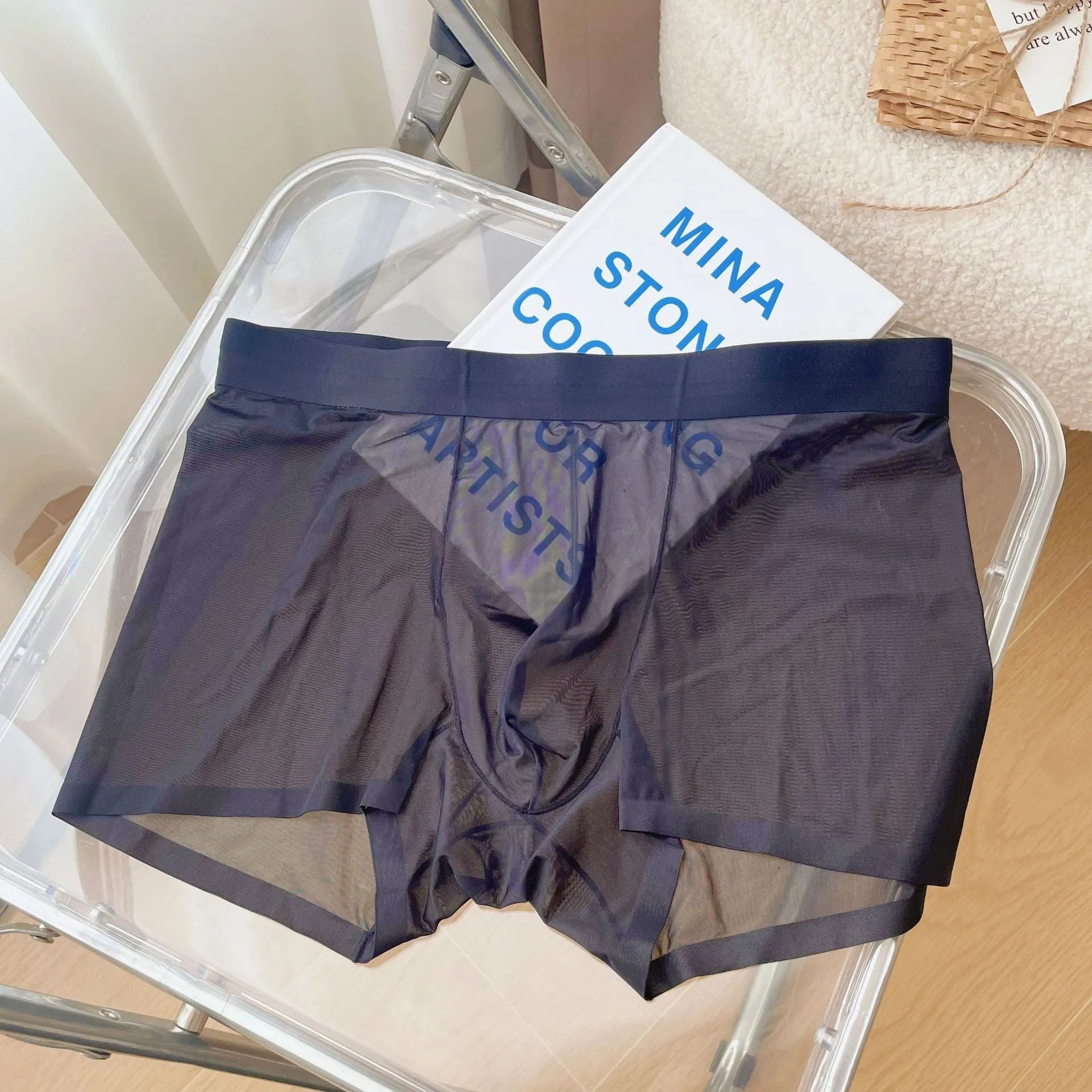 Men's thin grey seamless nylon boxer shorts laid flat, showing mid-waist and body-shaping design.