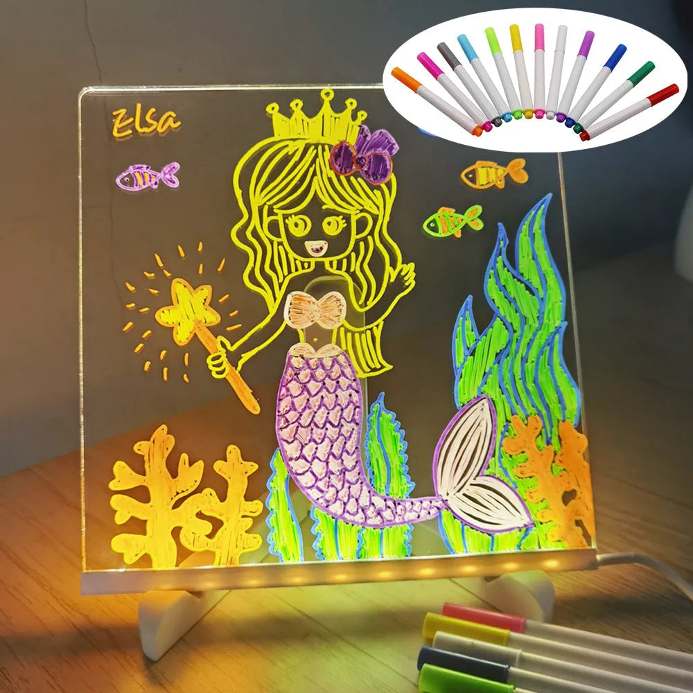 DIY acrylic LED message board lamp on a desk with colourful writing, showing USB cable and pens.