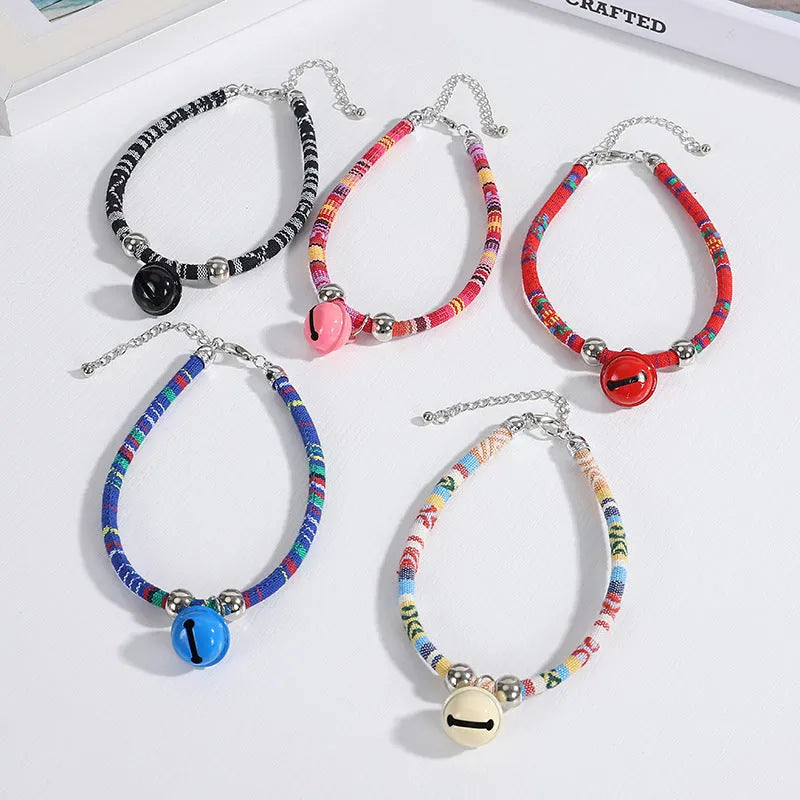An adjustable ethnic-style pet collar with a metal buckle and bell, shown in various colours.