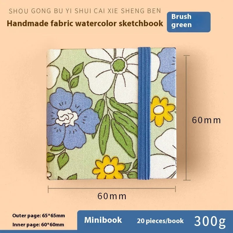 Feiluniao handmade fabric watercolour notebook with illustrated cover, open to show blank paper pages.