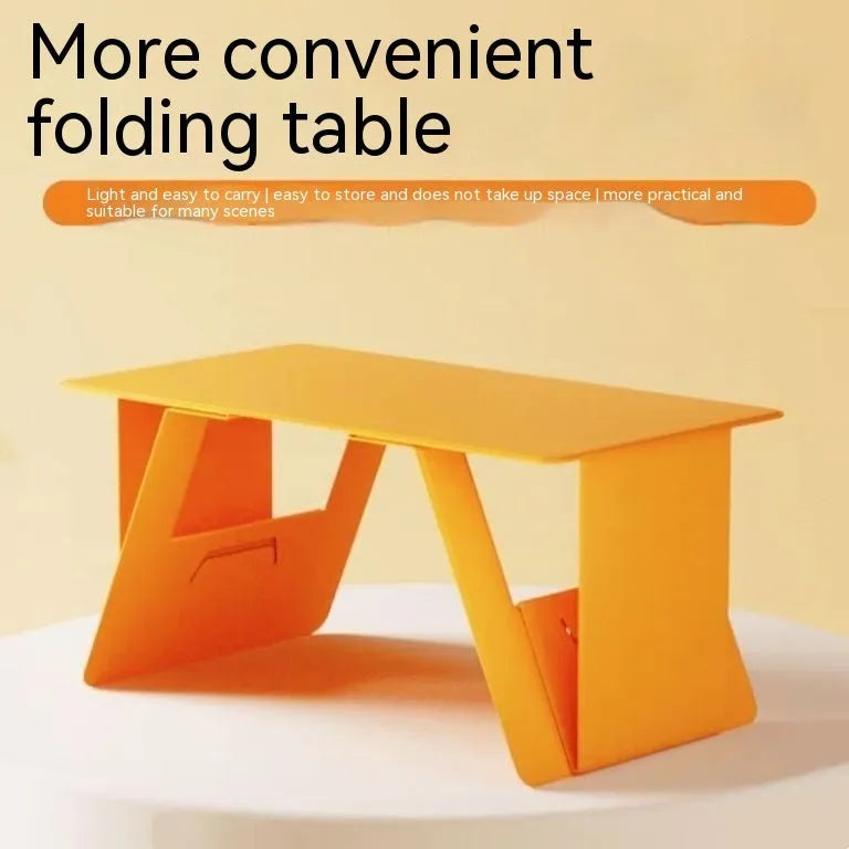 Foldable wooden laptop stand in black with storage area and folded legs on a flat surface