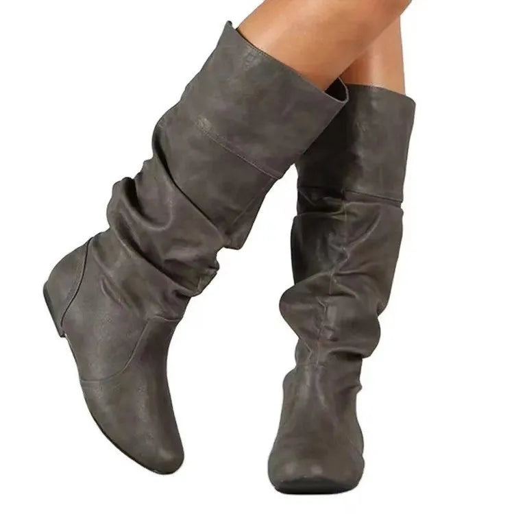 Women's black slip-on flat boots with a round toe and high cylinder shaft, showing the rubber sole.