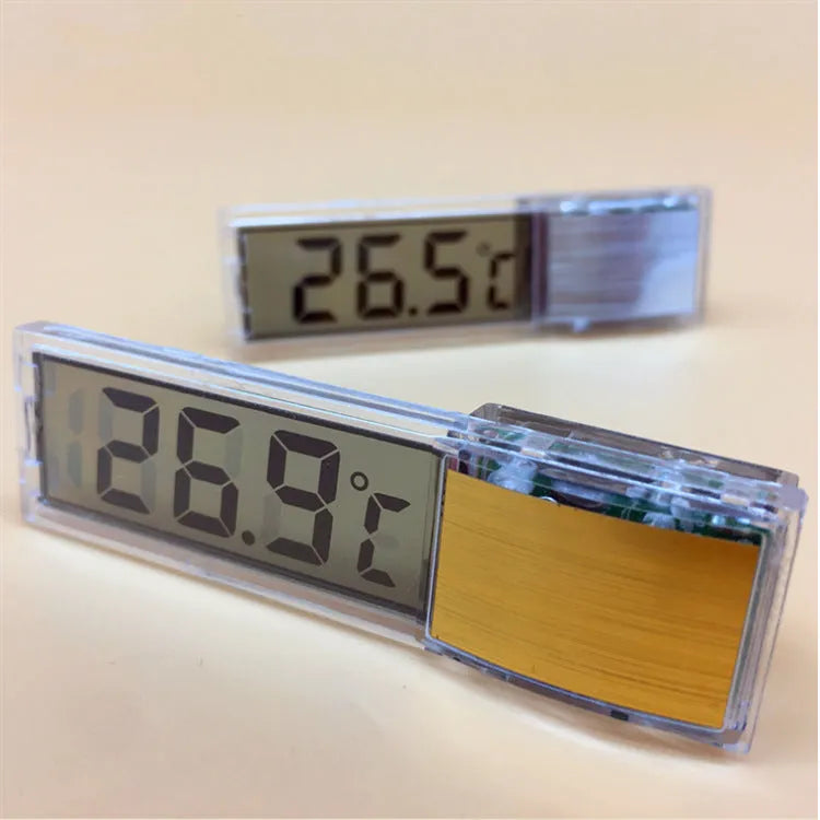 Gold digital thermometer mounted on aquarium glass showing temperature reading