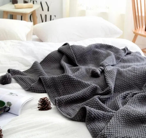 Acrylic knitted fringed blanket in beige colour on a sofa, showing texture and size.
