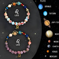 Set of twelve natural stone beaded bracelets laid out, each with a different zodiac sign charm or design.