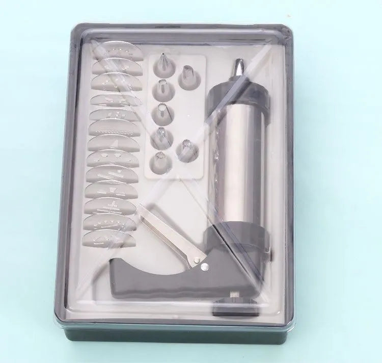Stainless steel biscuit press gun with assorted cookie mould discs and icing nozzles on a baking tray.