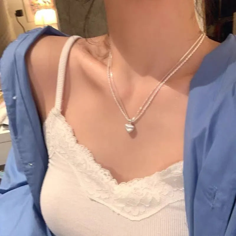 Double layer brushed heart shaped pendant necklace on adjustable silver tone chain.