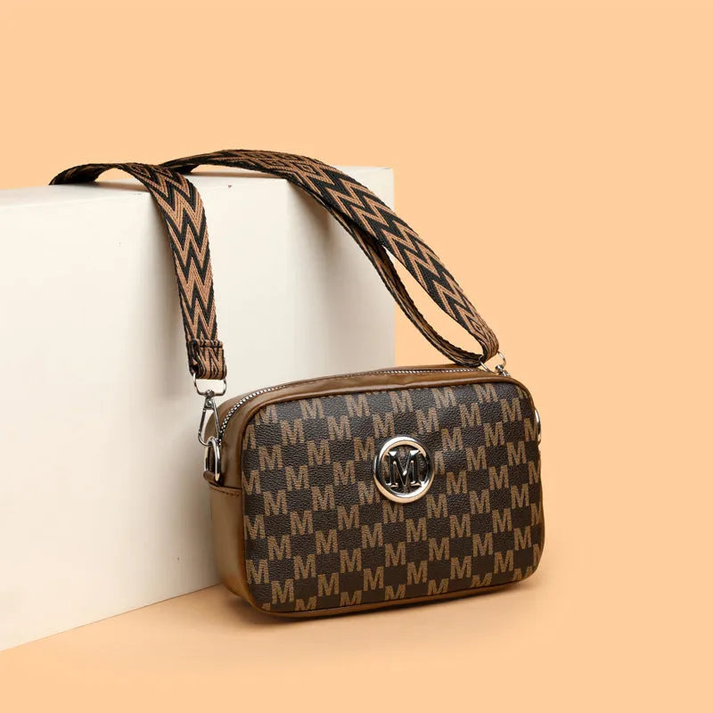 Black wide-strap crossbody bag made of PU leather, showing the three-dimensional outer pocket and adjustable shoulder strap.