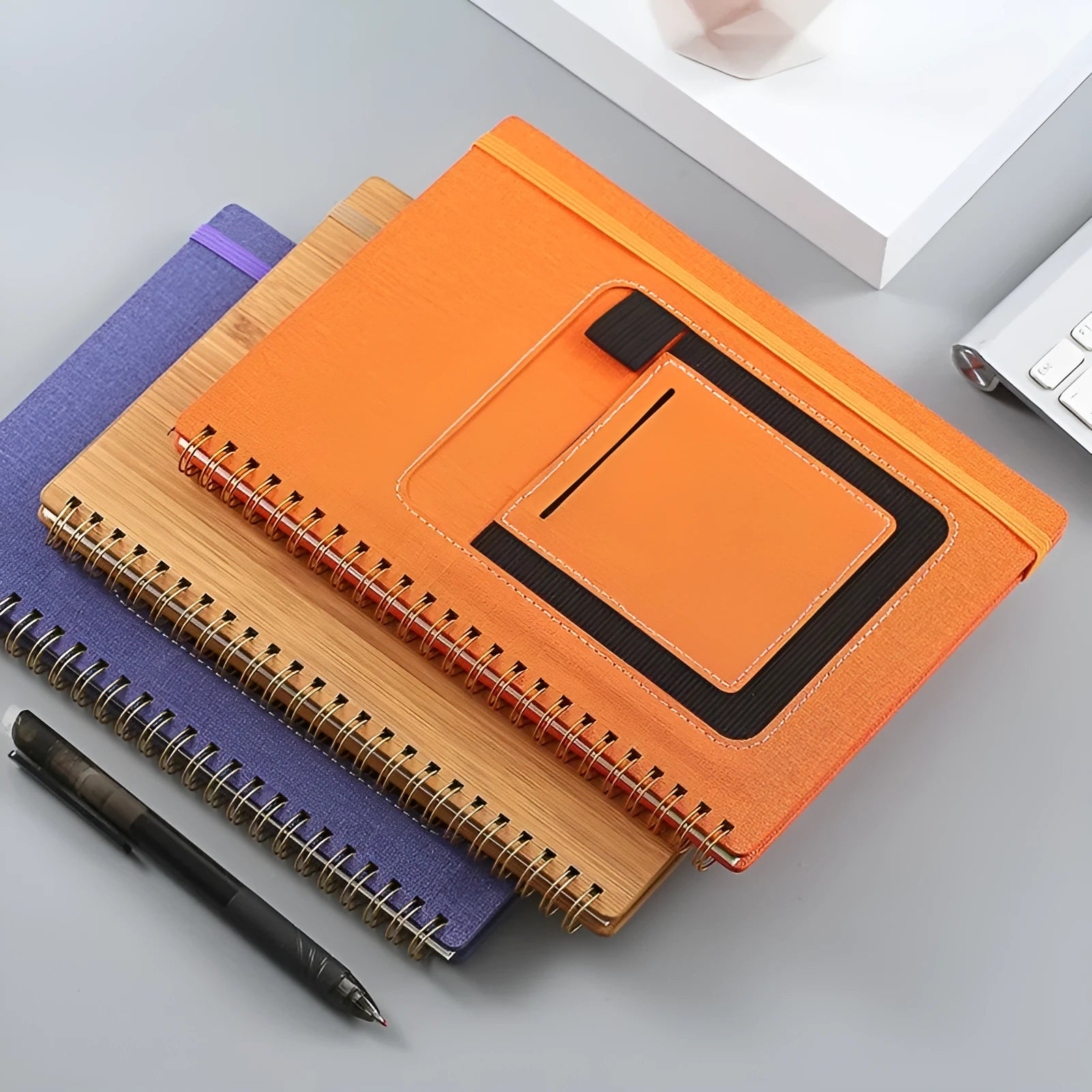 Erasable reusable coil notebook with rock stone paper, shown with a pen and cleaning cloth on a customisable cover.