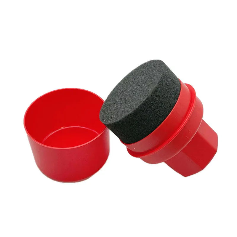 Black and red hand-held car tyre polishing sponge brushes with lids on a workbench.