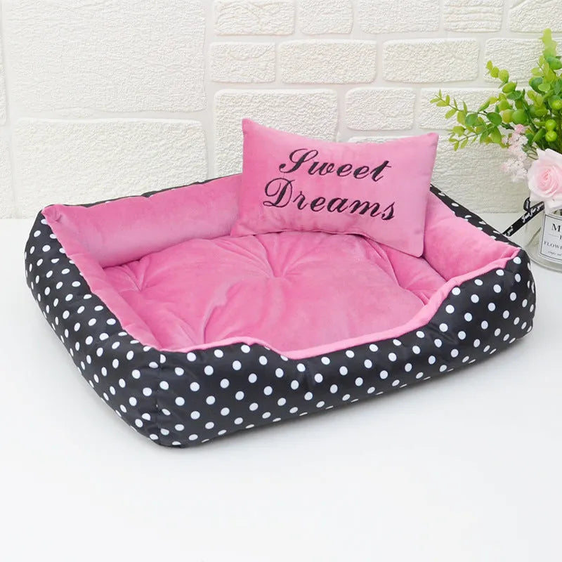 Polka dot square dog bed with matching embroidered pillow in grey, shown in a home setting.