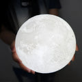 3D printed white moon lamp on wooden stand with touch-sensitive metal ring at base.