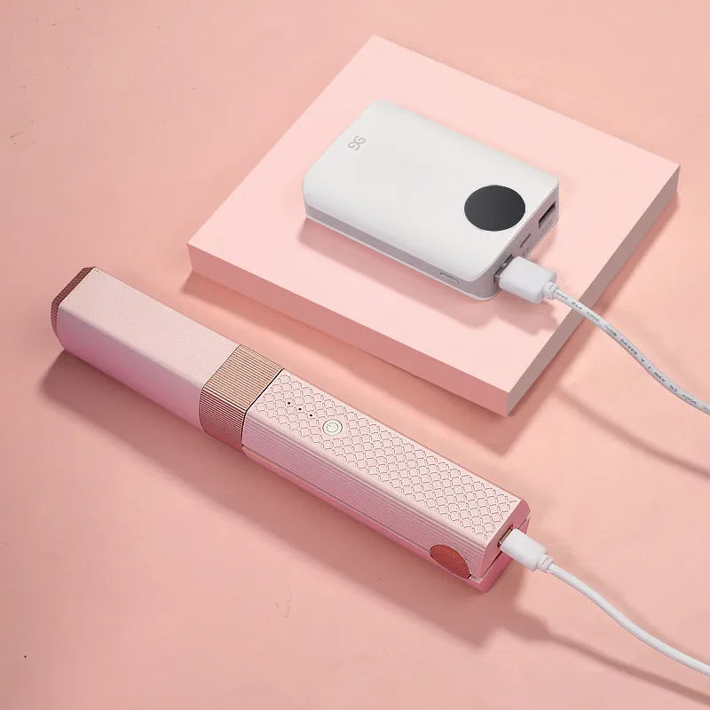 Pink and green mini cordless USB hair straightener with ceramic plates open on a white background.