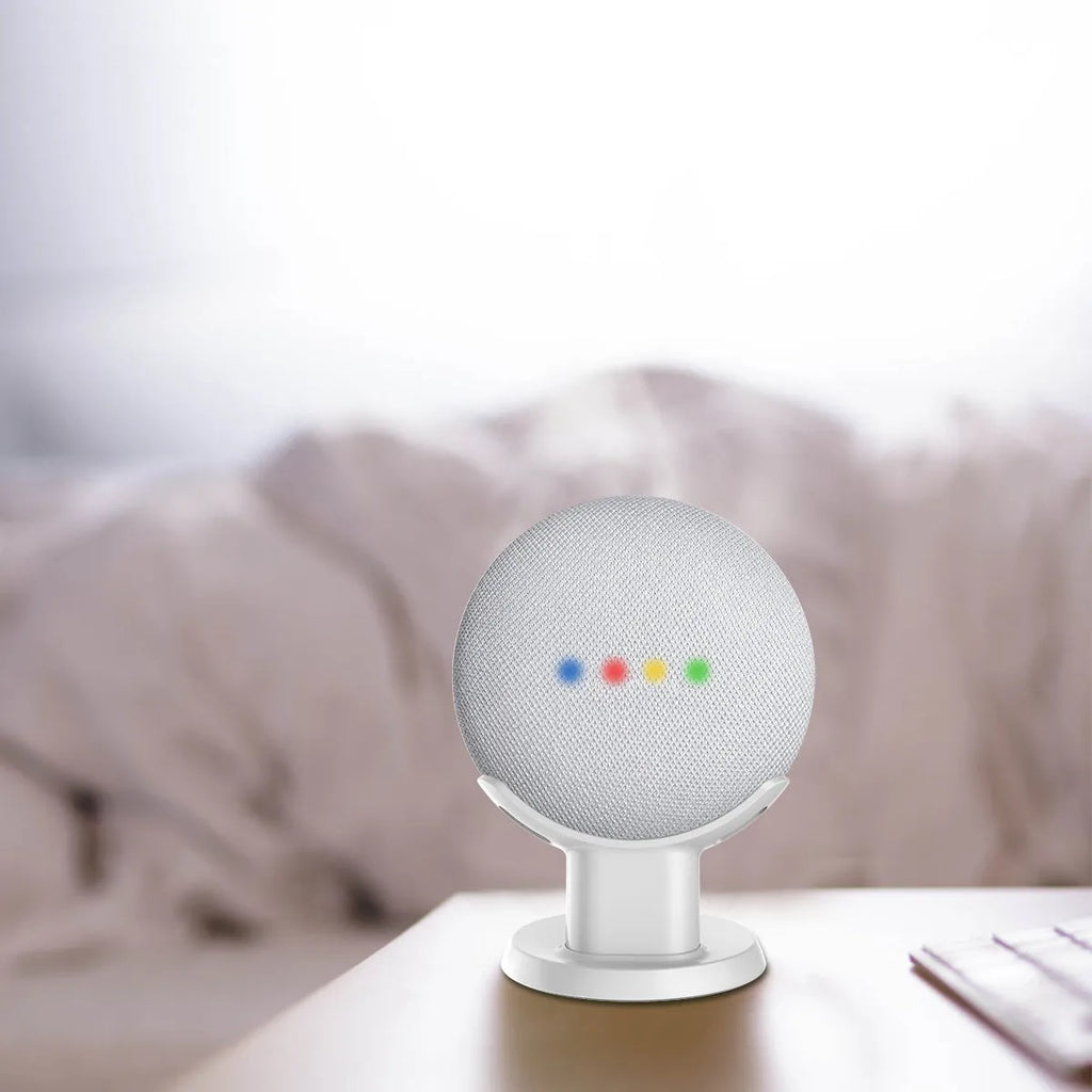 Black PlusAcc plastic stand holding a white Google Home Mini smart speaker on a wooden tabletop.