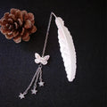 Silver pure copper feather bookmark with glowing luminous butterfly charm on a book.