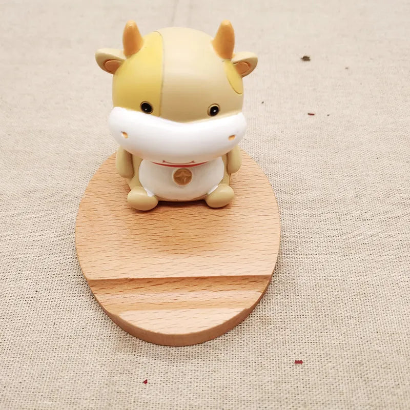 Beech wood and resin lazy bracket mobile phone holder in an animal design style on a desk.
