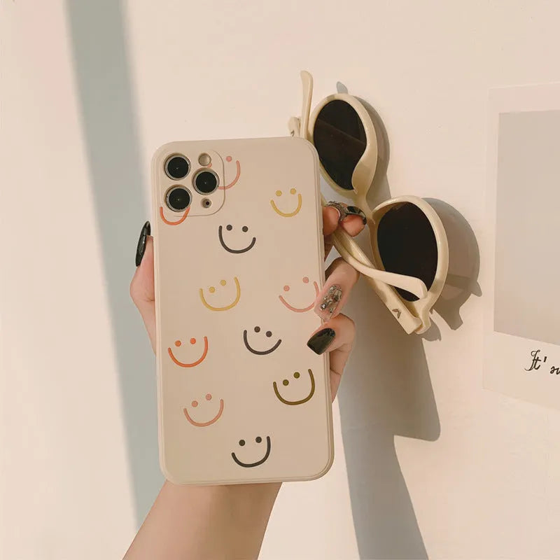 Simple TPU silicone iPhone case with painted smiley face and graffiti design on a table