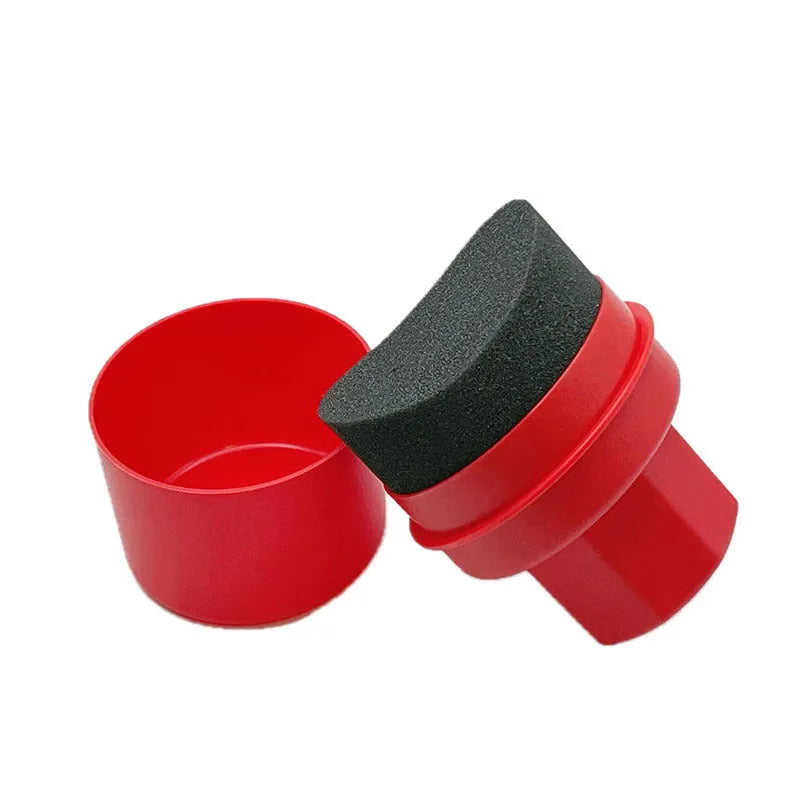 Black and red hand-held car tyre polishing sponge brushes with lids on a workbench.