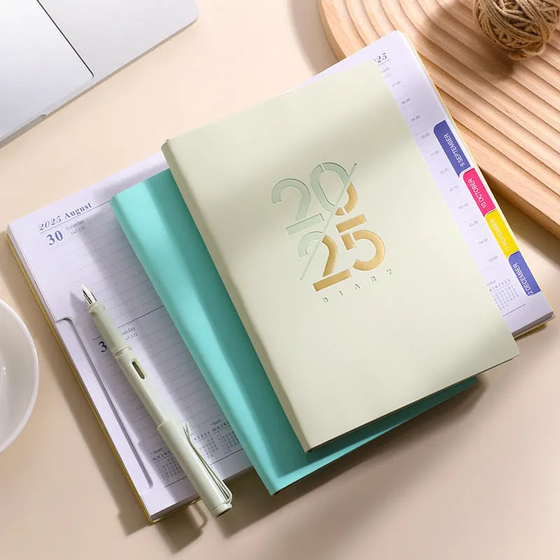 A5 daily planner notebook with soft faux leather cover in blue, lying open on a table.
