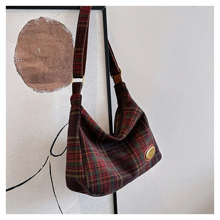 Red women's large wool shoulder bag with pendant on a table, showing square shape and sewing detail.