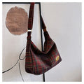 Red women's large wool shoulder bag with pendant on a table, showing square shape and sewing detail.