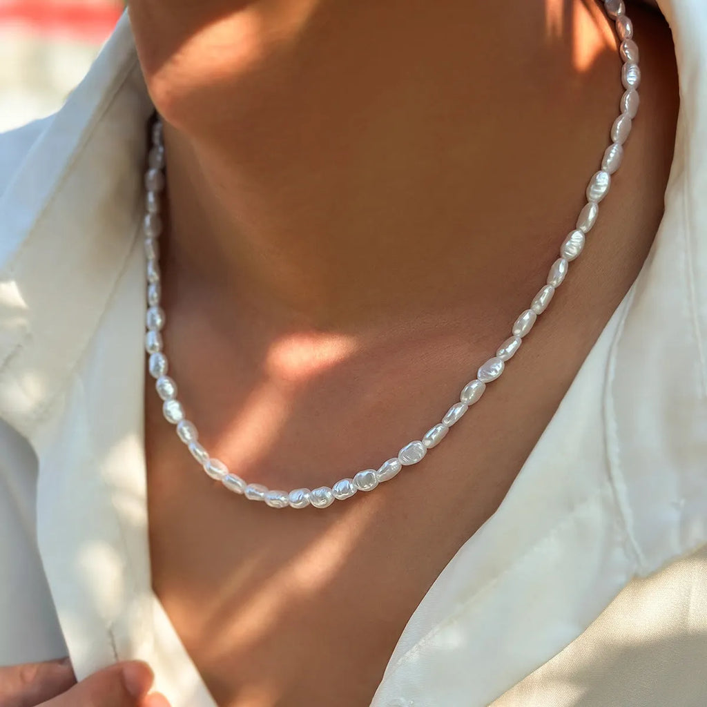 White U-shaped men's imitation pearl necklace with shellfish pendant on pearl chain.