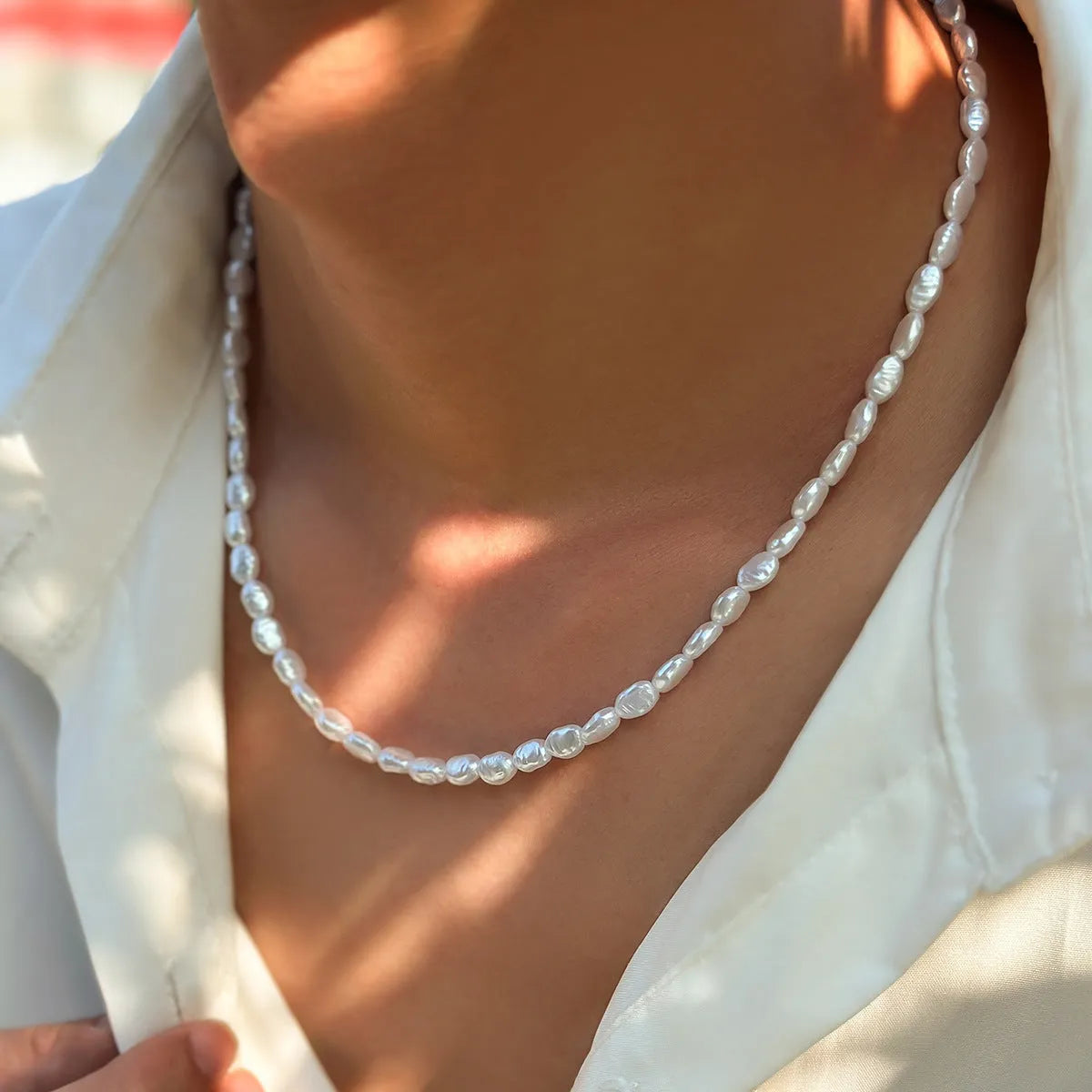White U-shaped men's imitation pearl necklace with shellfish pendant on pearl chain.