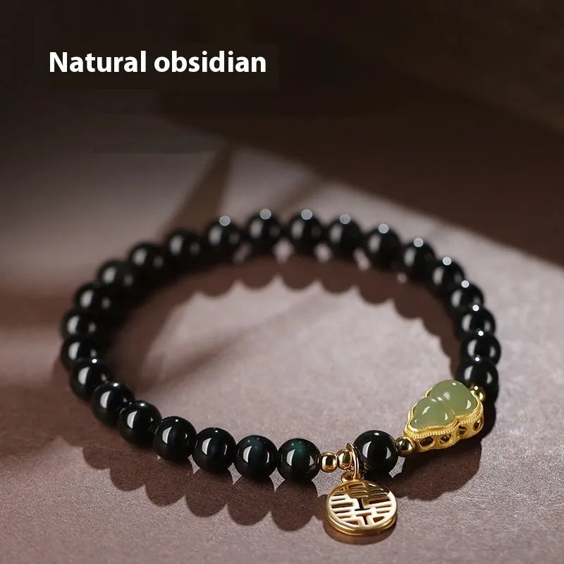 Black obsidian bead bracelet with a carved Hetian jade gourd charm, shown in geometric retro style.