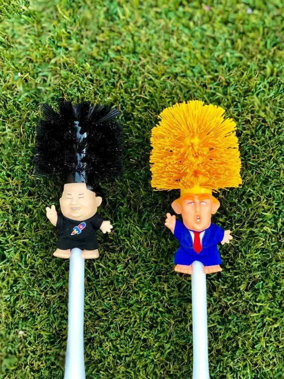 Yellow plastic Donald Trump toilet brush with hanging slot on handle.