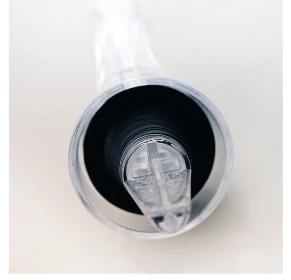 A clear acrylic wine aerator with a stainless steel filter, shown next to a wine glass.