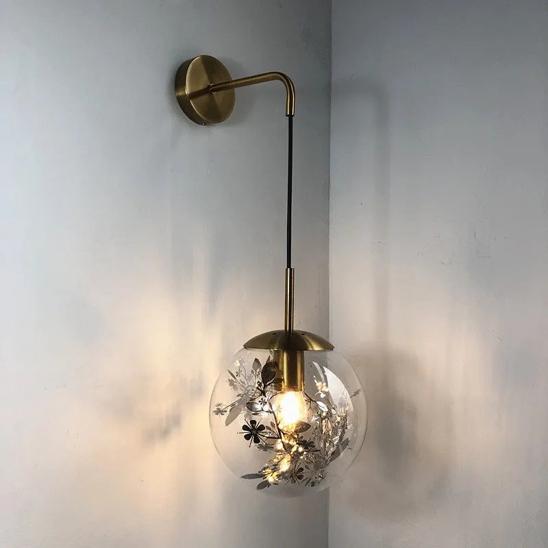 Modern glass wall mounted bedside lamp in golden flower finish on a white wall.